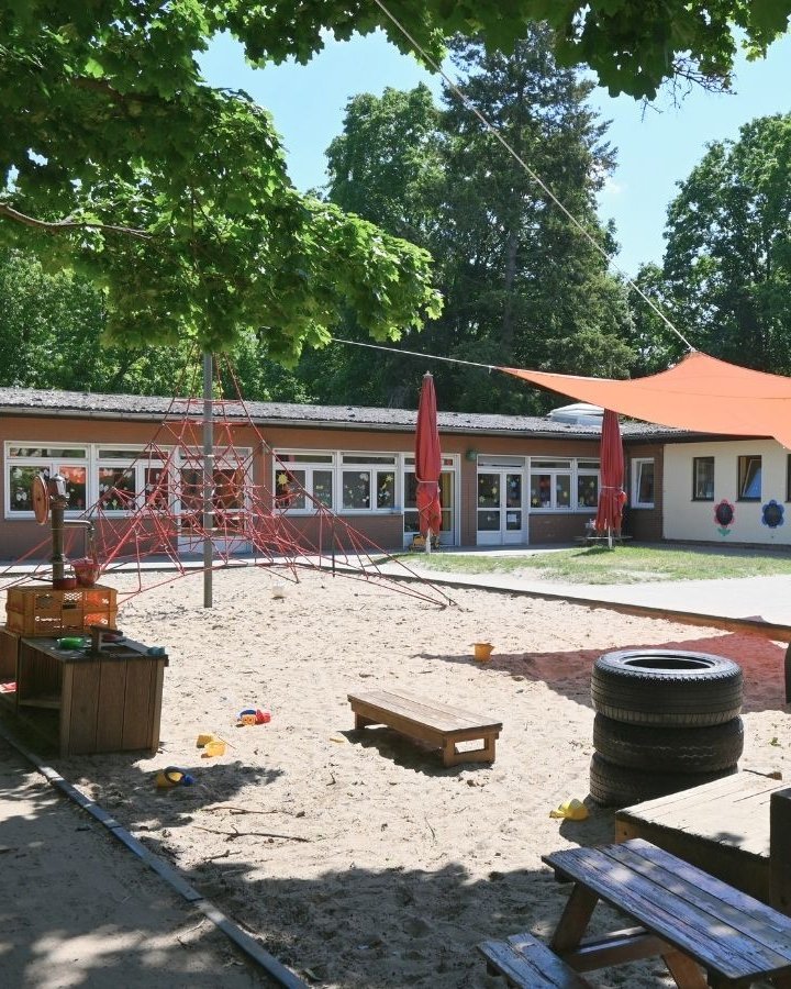 Außenbereich der Kita mit Sandkasten und Klettergerüst